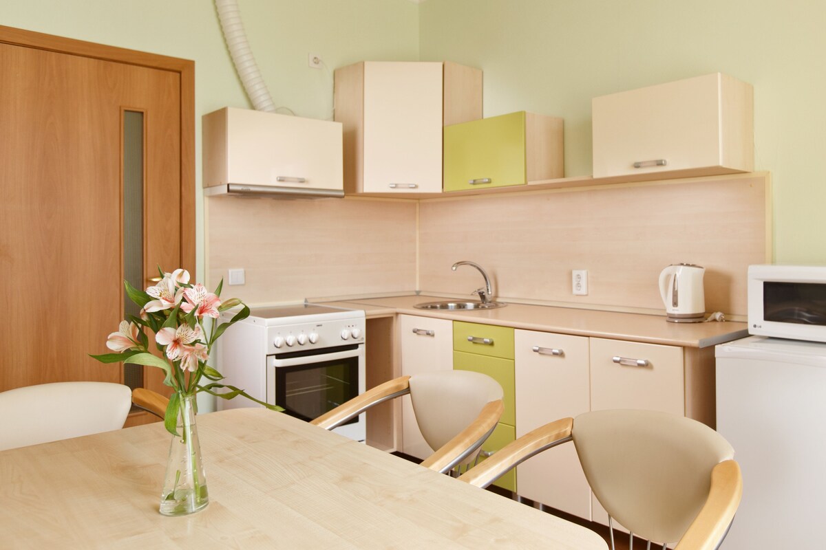 Una cocina compacta con una mesa de comedor, sillas, una estufa blanca, un lavamanos y un microondas.