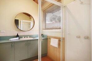 Een badkamer met een wastafel, spiegel en douche.
