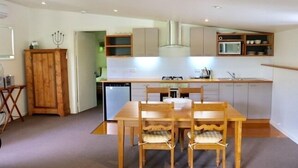Une cuisine compacte avec un coin repas, des meubles en bois, un four à micro-ondes et un lave-vaisselle.
