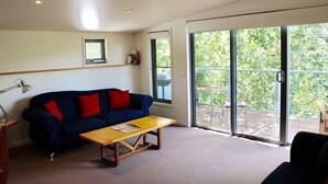 Un salon moderne avec un canapé, une table basse en bois et une grande porte-fenêtre coulissante donnant sur un espace extérieur.