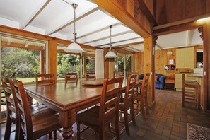 A spacious dining area with a wooden table and chairs, large windows, and a view of the outdoors. - Warrina - Over Looking Ovens River (Bright)