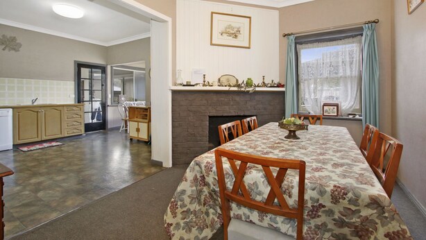 A dining area with a table set for four, a fireplace, and a view through a window with curtains. - Le Chateau - Centrally located (Bright)