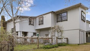 A two-story building with a symmetrical facade, large windows, and a visible garage door. - Le Chateau - Centrally located (Bright)