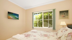 A bedroom with a bed, a window with curtains, a painting on the wall, and a lamp. - River's Reach - Bright (Bright)