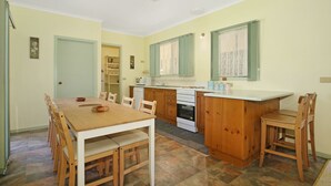 A compact kitchen with a dining area, wooden cabinets, and a built-in oven. - River's Reach - Bright (Bright)