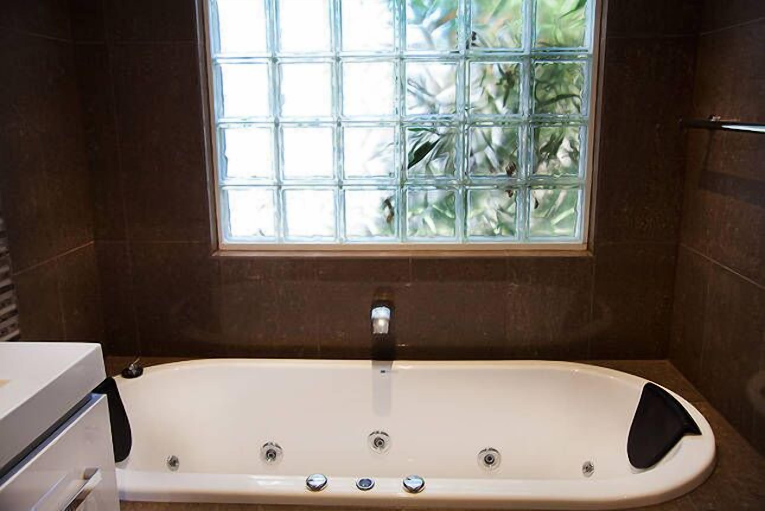 A modern bathroom with a freestanding bathtub, a window with a view of greenery, and a towel rack.