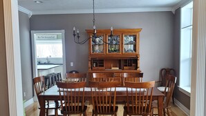 A dining area with a wooden table and chairs, a glass cabinet, and a chandelier.