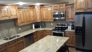 A kitchen with wooden cabinets, granite countertops, stainless steel appliances, and a dishwasher.