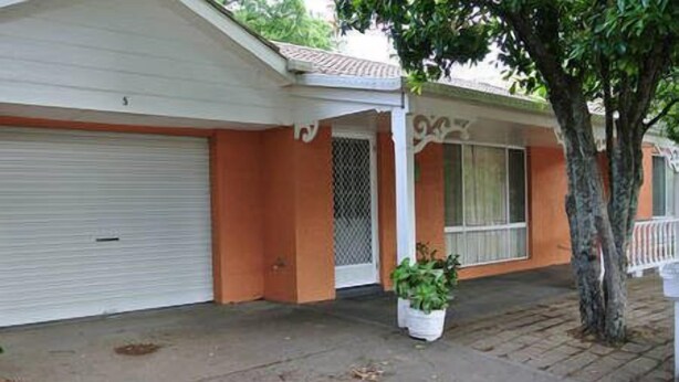 A single-story house with a garage door, a small porch with a potted plant, and a tree in front. - Onocay House (Bright)