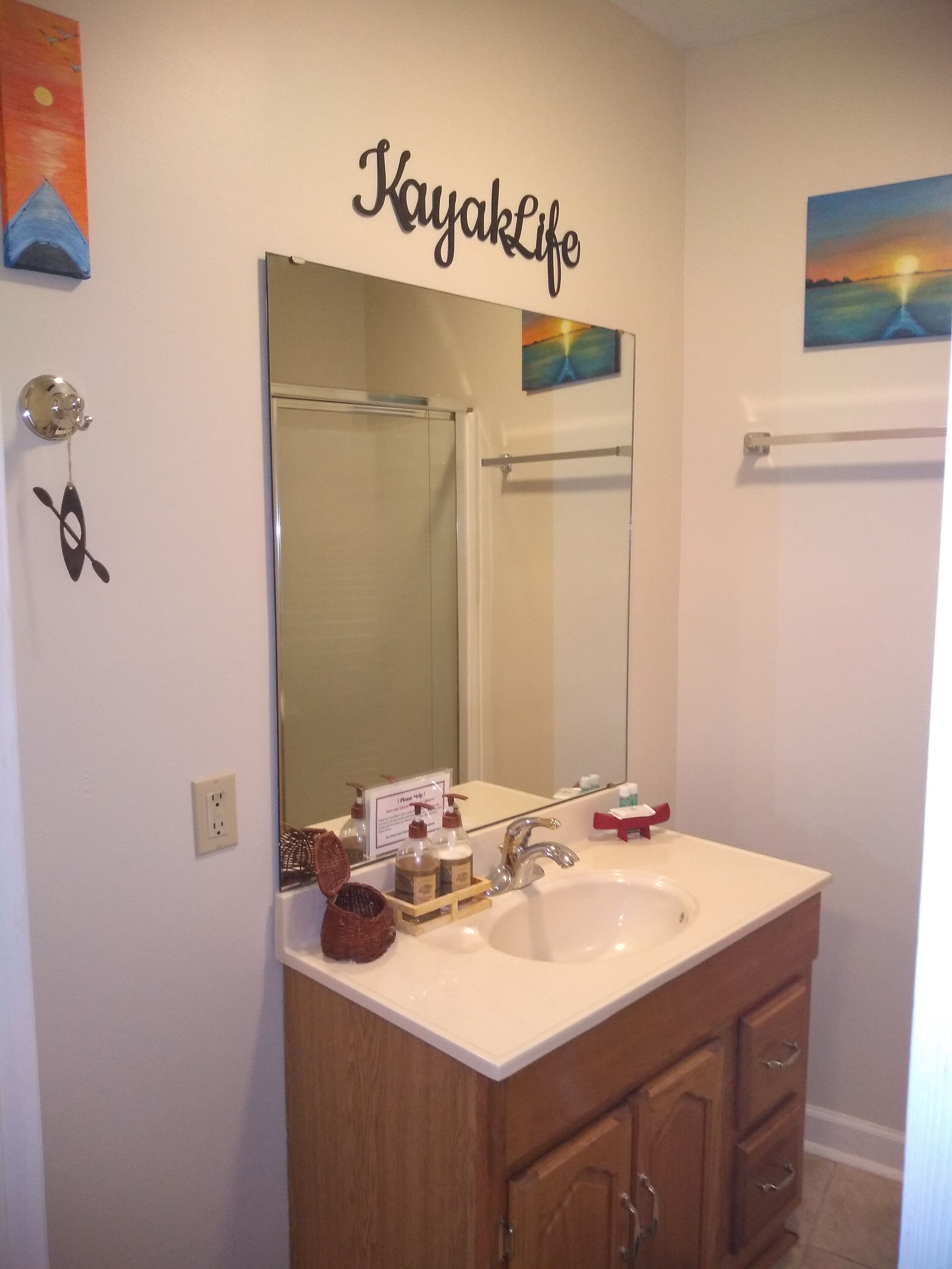 A bathroom with a large mirror, a sink, and a towel rack.