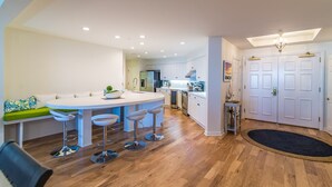 A modern kitchen with a central island, bar stools, and a dining area with a sofa. - $150 activities - E-gift card when you book - Contemporary Oceanfront Luxury | M2003 (Myrtle Beach)