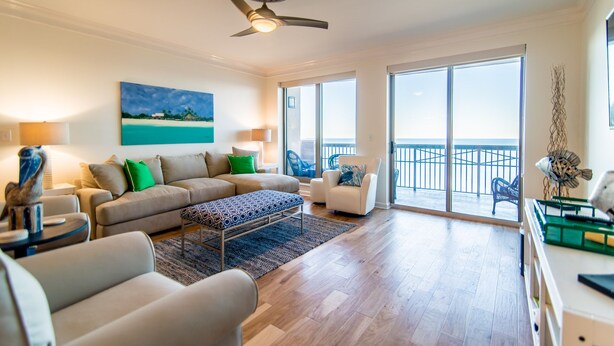 A spacious living room with a large sofa, a coffee table, and a balcony with a view of the ocean. - $150 activities - E-gift card when you book - Contemporary Oceanfront Luxury | M2003 (Myrtle Beach)