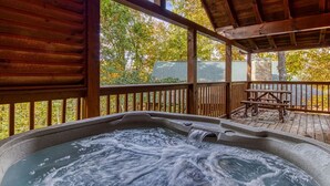 A hot tub under a wooden deck with a view of trees and a picnic table. - The Nut House, Hot Tub, $560 FREE tickets each paid day (Pigeon Forge)