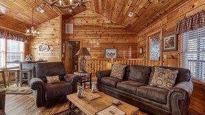 A cozy log cabin interior with a wooden ceiling, leather sofas, a dining table, and a fireplace. - The Nut House, Hot Tub, $560 FREE tickets each paid day (Pigeon Forge)