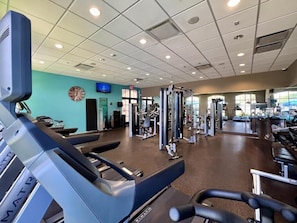 Un gimnasio con cintas de correr, máquinas de pesas y un reloj de pared.