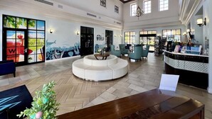 A spacious lobby with a central seating area, a reception desk, and artwork on the walls.