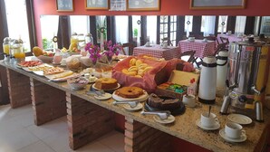 Un bufé de desayuno con diferentes opciones de comida, una máquina de café y un mantel a cuadros.