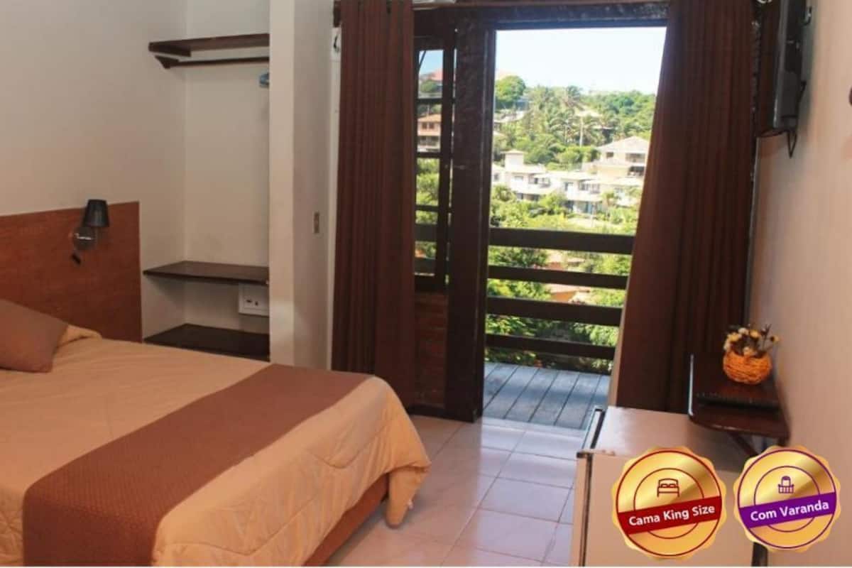 A bedroom with a bed, a nightstand, a window with curtains, and a view of buildings outside.