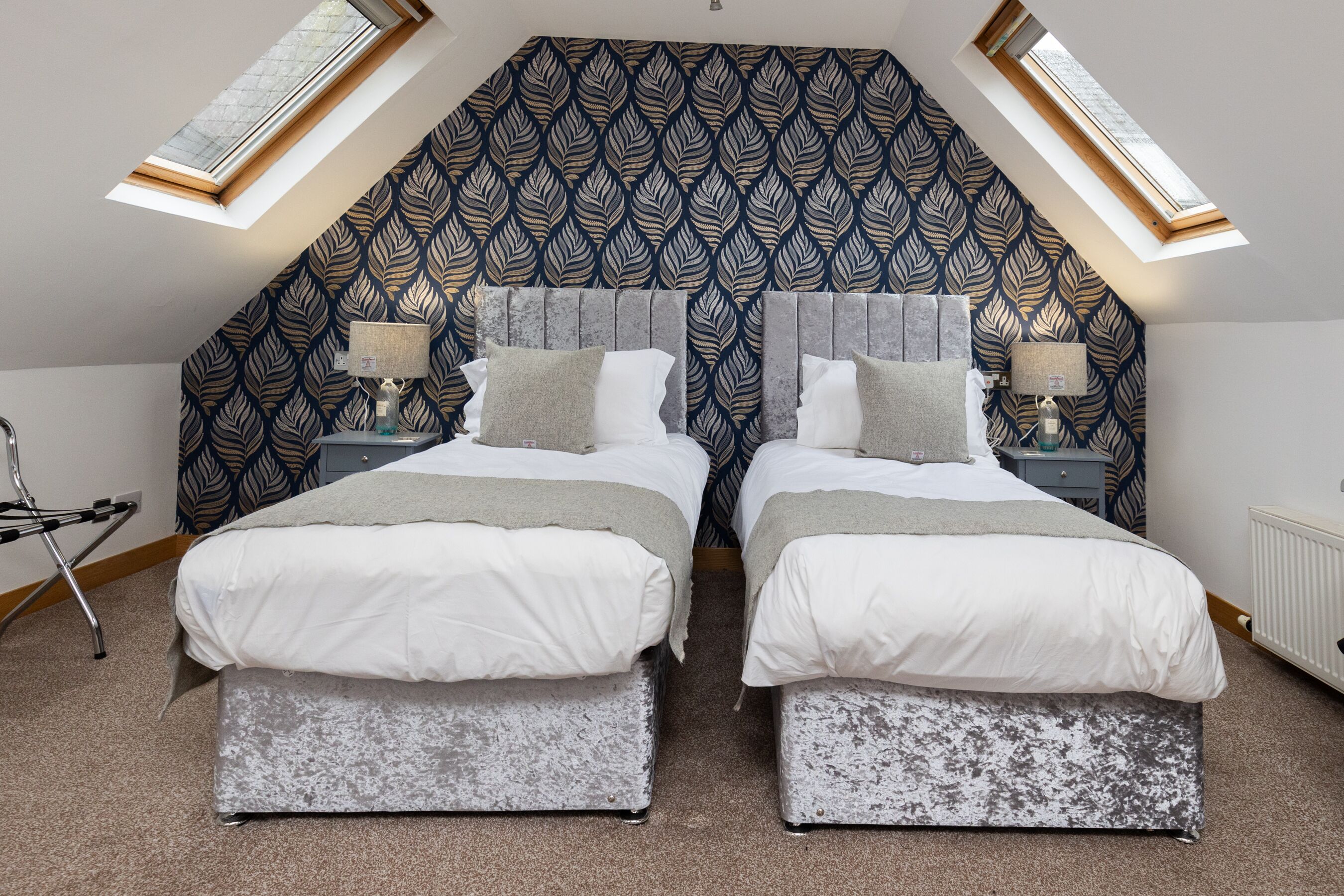 A bedroom with two beds, a patterned ceiling, and skylights.