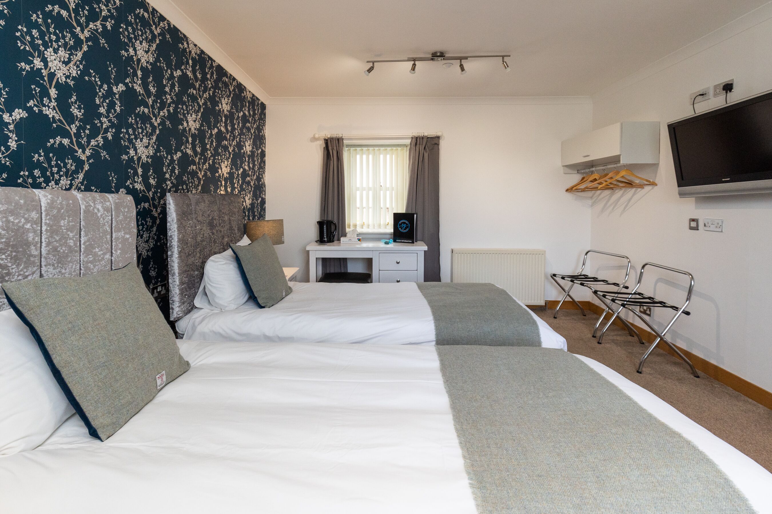 Une chambre d’hôtel avec deux lits, un bureau, une télévision et un radiateur.