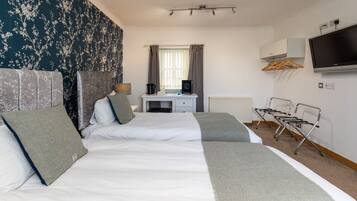 Une chambre d’hôtel avec deux lits, un bureau, une télévision et un radiateur.