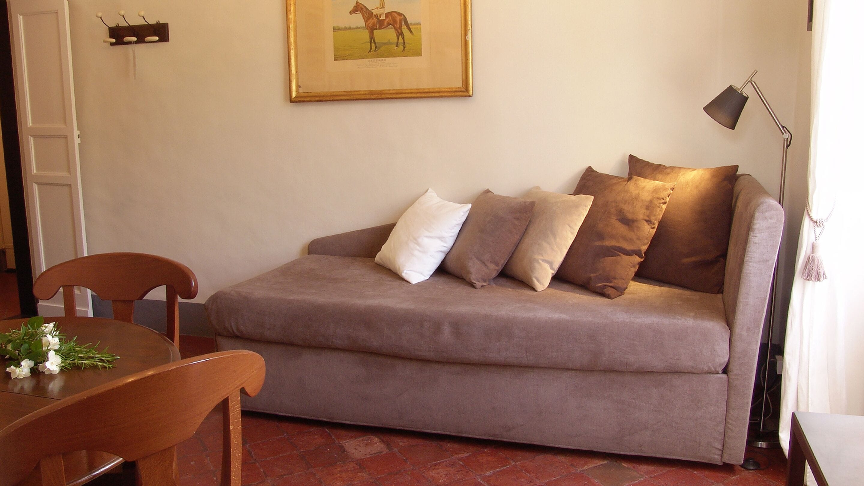Une pièce chaleureuse avec un canapé, une table à manger et des chaises, ainsi qu’un tableau encadré au mur.
