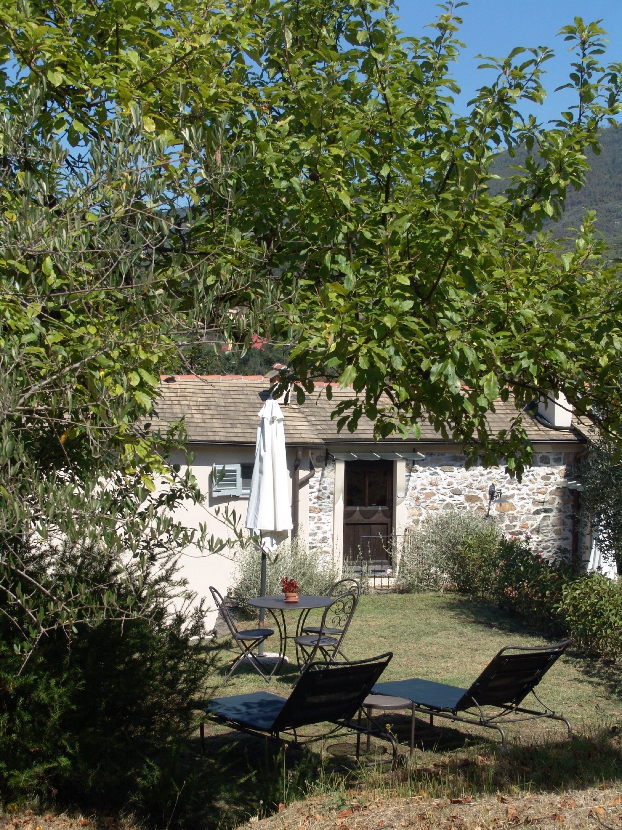 Una casa de piedra con un muro de piedra, una puerta de madera y un pequeño jardín con una mesa y sillas.