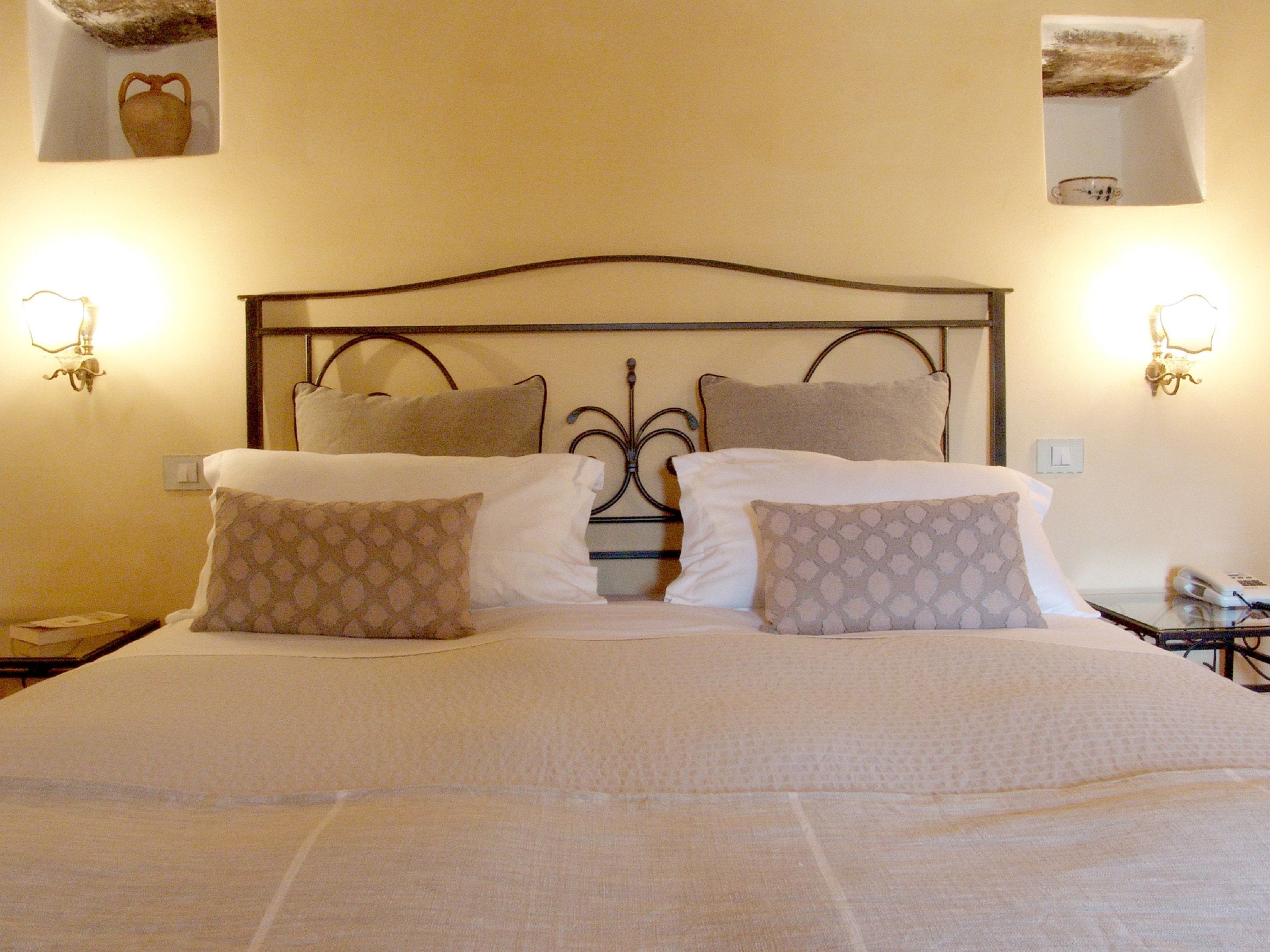 Una cama bien hecha con almohadas estampadas y un cabecero de metal.
