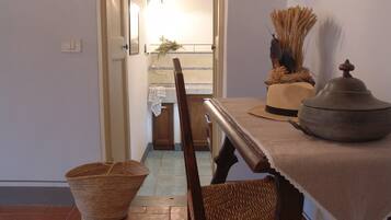 A dining area with a table set for two, a wicker basket, and a wooden chair.