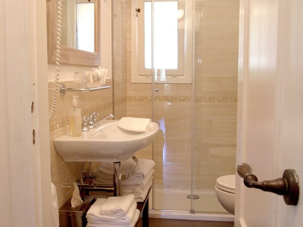 Une salle de bain équipée d’un lavabo, d’un miroir et d’une douche à parois en verre.