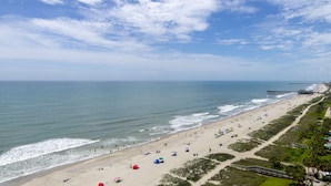 A beach with a pier extending into the water, sandy beach, and a clear sky. - Gorgeous Remodeled 3BR, 2BA Camelot Oceanfront. In the heart of Myrtle Beach! (Myrtle Beach)