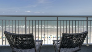 A balcony with wicker chairs overlooking a beach with umbrellas. - Gorgeous Remodeled 3BR, 2BA Camelot Oceanfront. In the heart of Myrtle Beach! (Myrtle Beach)