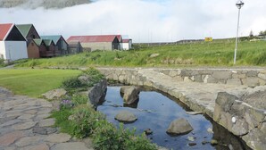 A stone bridge over a small stream with a stone pathway leading to it. - visitHOMES Faroe Islands (Leirvik)