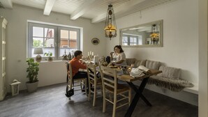 A dining area with a wooden table and chairs, a sofa, and a hanging light fixture. - visitHOMES Faroe Islands (Leirvik)