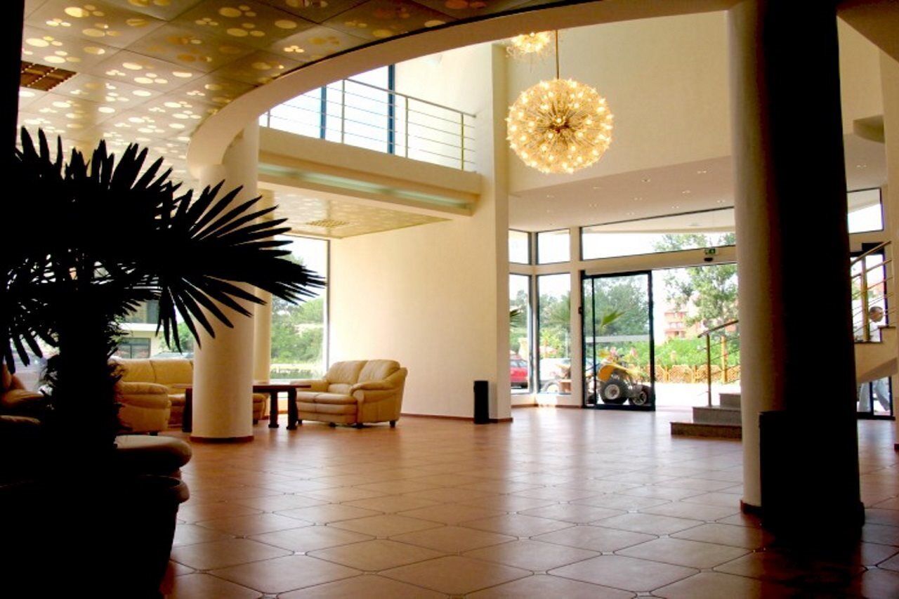 A spacious lobby with a high ceiling, large windows, and a central chandelier.