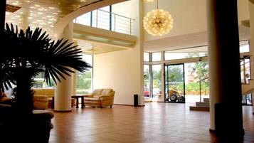 A spacious lobby with a high ceiling, large windows, and a central chandelier.