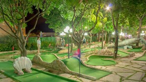 A miniature golf course with green artificial turf, stone pathways, and various obstacles. - Hotel Shipka Beach (Sunny Beach)