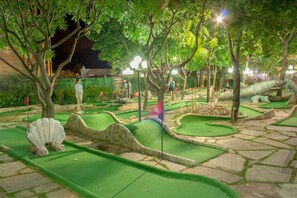A miniature golf course with green artificial turf, stone pathways, and various obstacles. - Hotel Shipka Beach (Sunny Beach)