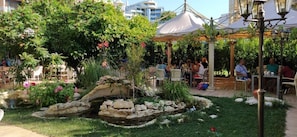 An outdoor garden area with a gazebo, seating arrangements, and a small water feature. - Hotel Shipka Beach (Sunny Beach)