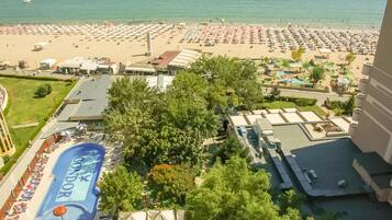 A resort with a large pool area, a beach, and a view of the ocean.