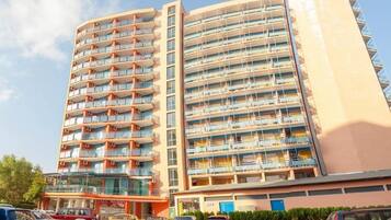 A multi-story hotel with balconies, a ground-level restaurant, and a parking area.