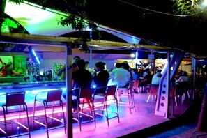 An outdoor bar area with metal chairs and tables, a counter with bottles, and a canopy overhead. - Hotel Shipka Beach (Sunny Beach)