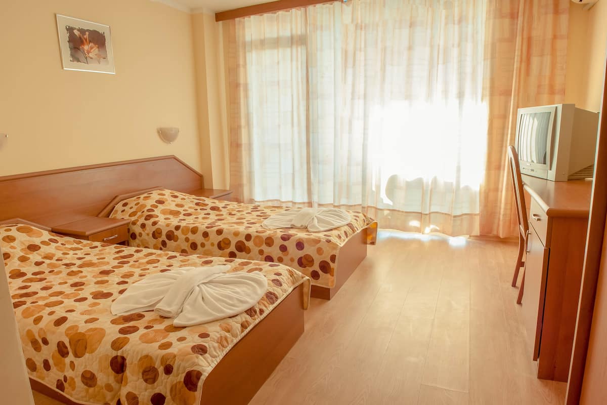 Habitación de hotel con dos camas, televisor y un armario de madera.