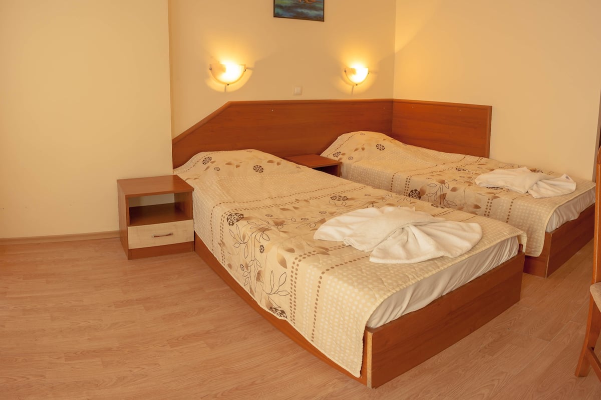 Cama doble con ropa de cama floral, mesitas de noche e iluminación en la pared.