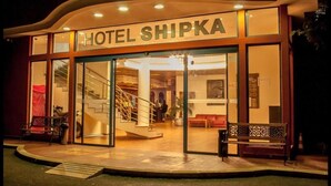 The exterior of Hotel Shipka with a modern design, featuring a prominent entrance, a staircase leading to the lobby, and a seating area outside. - Hotel Shipka Beach (Sunny Beach)