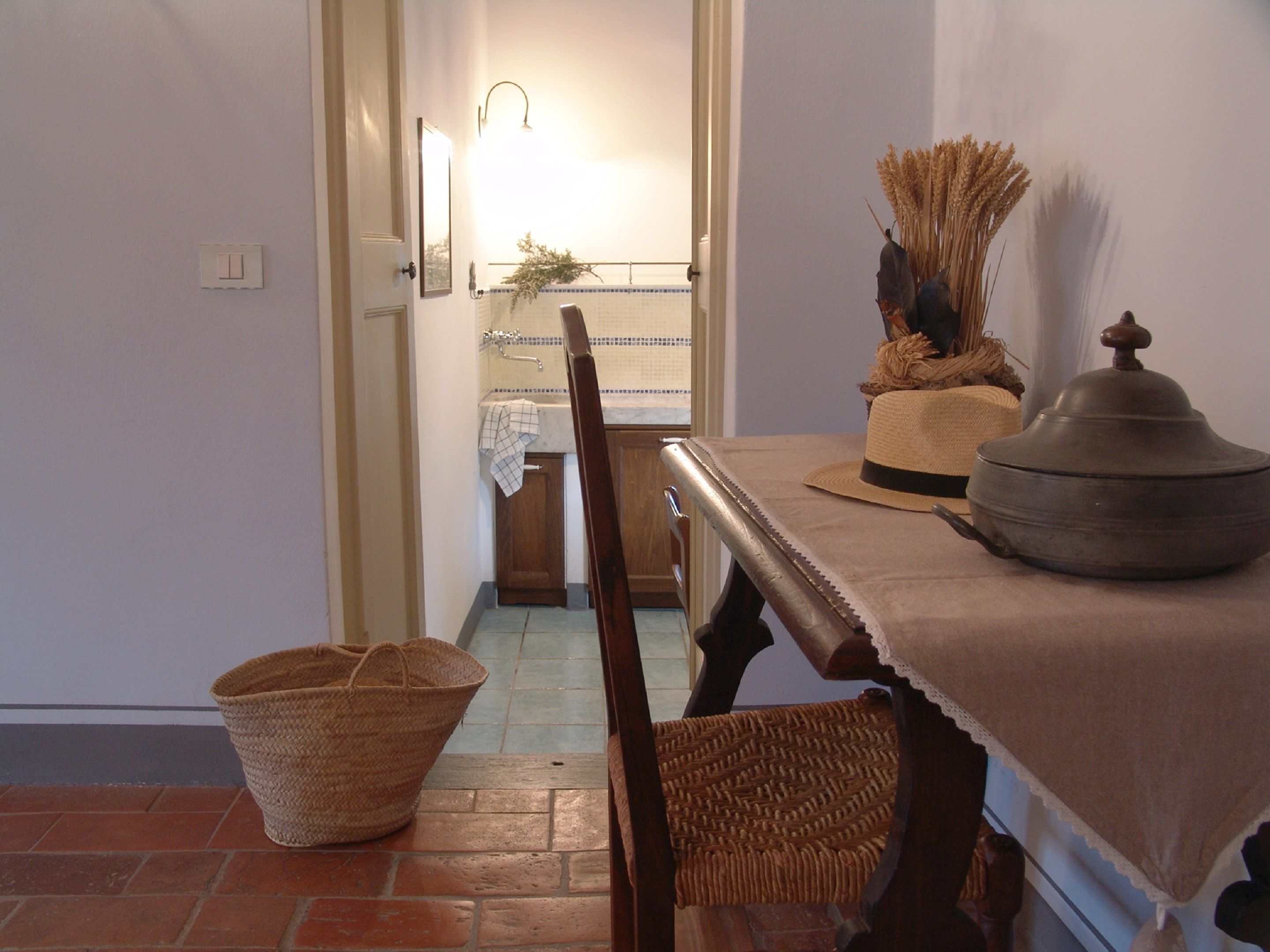 A dining area with a table set for two, a wicker basket, and a wooden chair.