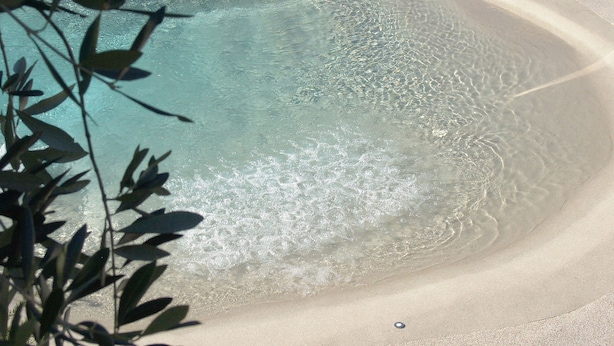 On peut clairement voir une plage de sable fin, avec de douces vagues venant lécher le rivage.