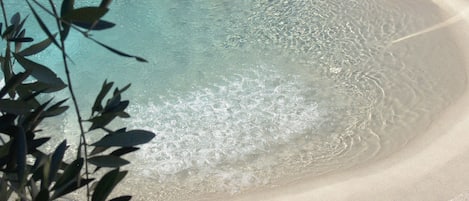 En säsongsöppen utomhuspool, parasoller och solstolar