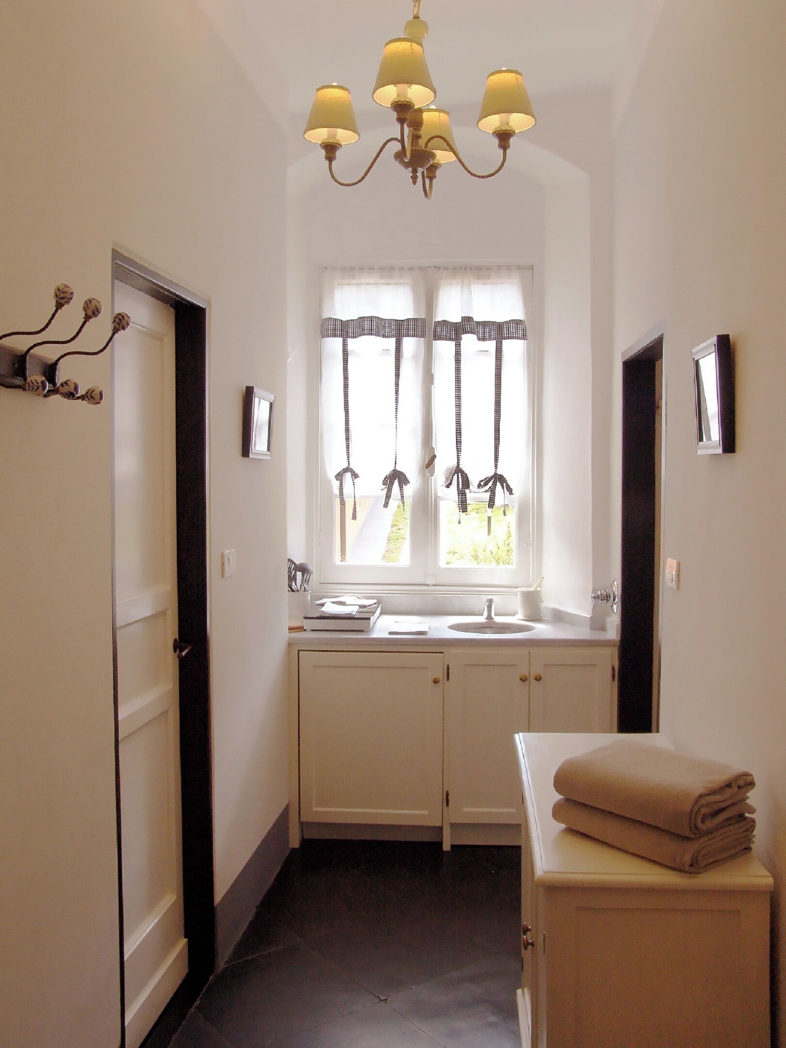 Un couloir étroit avec une fenêtre, un lavabo et une pile de serviettes.