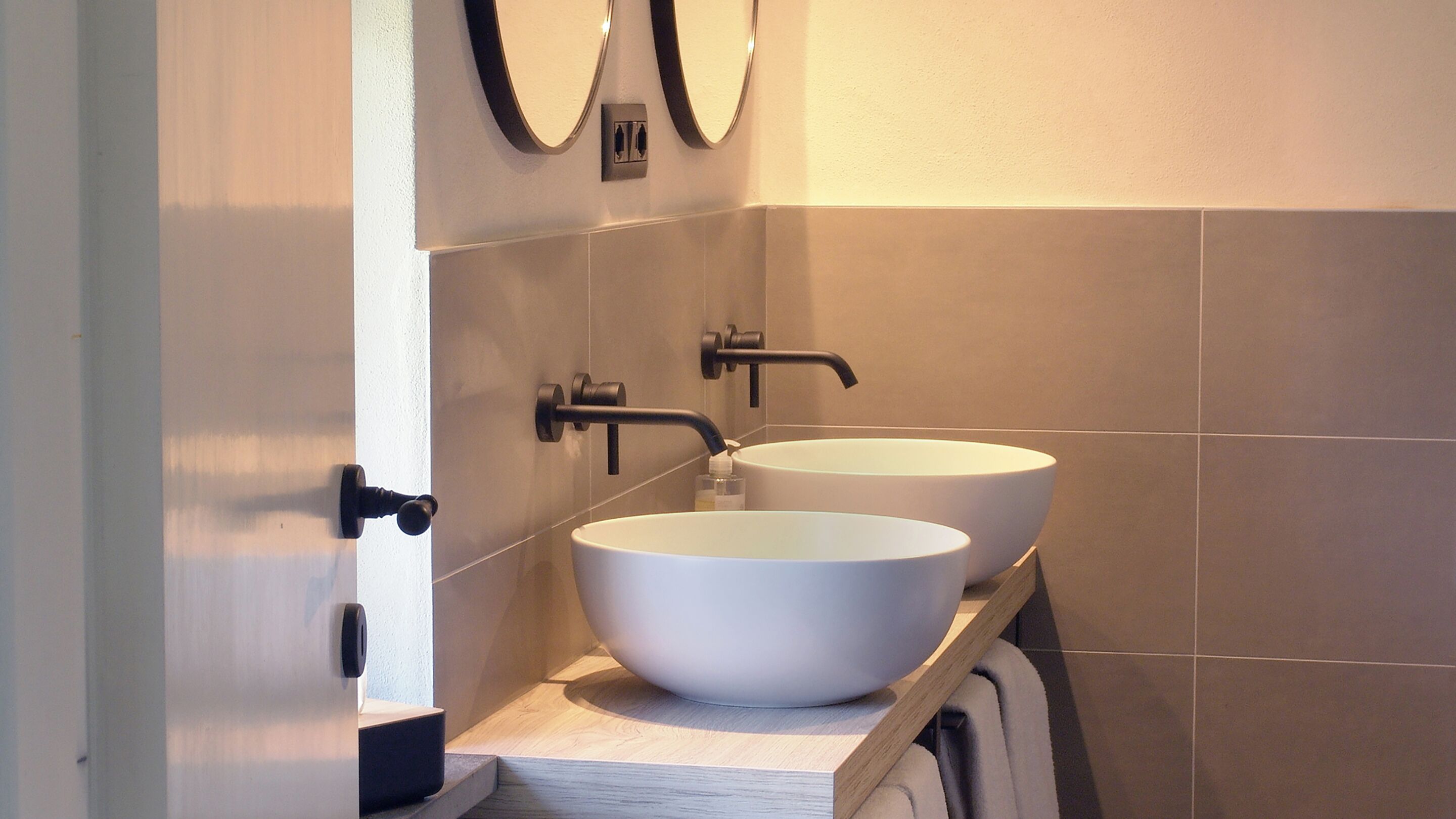 A bathroom with two white sinks, a black faucet, and a towel rack.